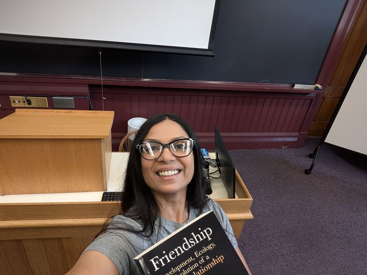 Lekshmi at a lectern holding the book Friendship