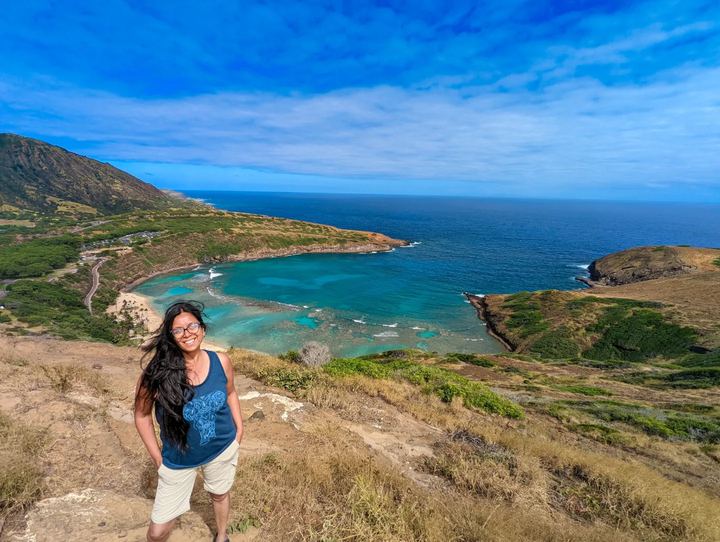 Lekshmi on a hillside above a turquoise bay