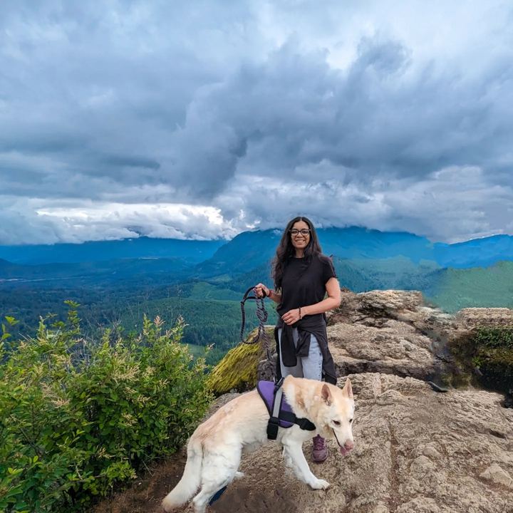 Lekshmi with a white dog on a rocky mountain overlook